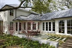 a large white house with lots of windows and plants in front of the door area