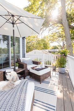 a patio with wicker furniture and an umbrella over the seating area on the deck