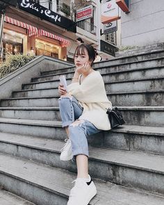 a woman sitting on the steps looking at her cell phone