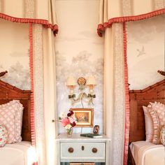 two twin beds in a bedroom with pink and white decor on the walls, along with matching drapes