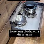 a kitchen counter with pots and pans sitting on it's bottom shelf next to an oven