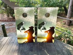 two cornhole game boards sitting on top of a wooden deck with trees in the background