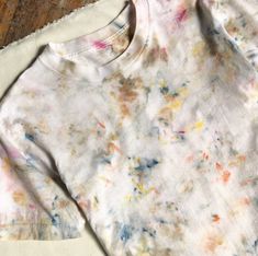 a white shirt with multicolored paint splattered on it