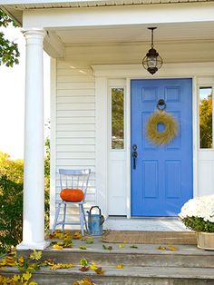 a blue front door with a wreath and two chairs on the steps next to it