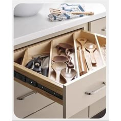 an open drawer with utensils and spoons in it on a counter top