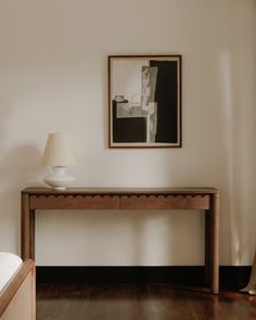 a wooden table sitting next to a white lamp on top of a hard wood floor