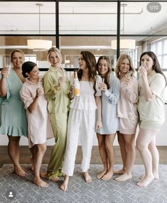 a group of women standing next to each other holding drinks and posing for the camera