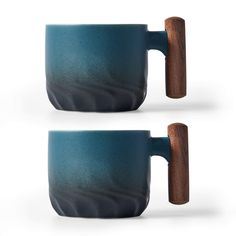 two coffee mugs with wooden handles are shown in the same color as each other