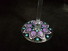 a wine glass with purple, blue and white designs on the bottom sitting on a black surface