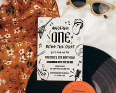 an orange and white birthday card next to a record player's sunglasses on top of a bed