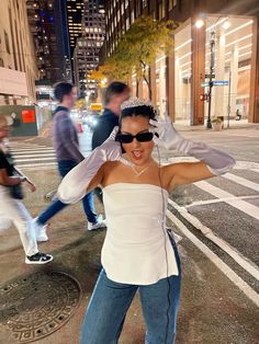 a woman in white shirt and jeans standing on street with headphones around her ears