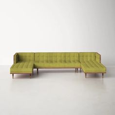 an l - shaped sectional sofa with wooden legs and green fabric upholstered to the back