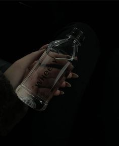 a person holding a bottle in the dark