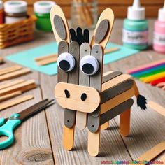 a wooden horse made out of popsicle sticks on a table with scissors and glue