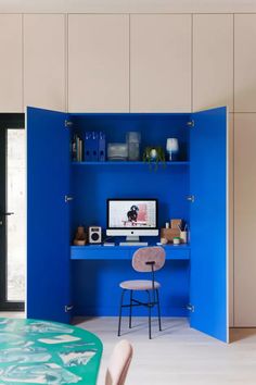 a room with a desk, chair and computer on the wall next to a blue bookcase