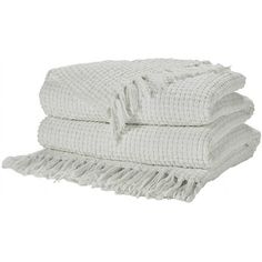 three white towels stacked on top of each other in front of a white background with fringes