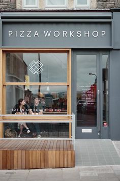 people are sitting in the window of a pizza shop