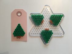 two pieces of plastic beaded christmas tree decorations next to a pink tag on a white surface