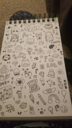 a notebook with doodles on it sitting on top of a table next to a person