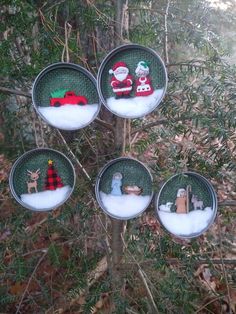 four ornaments are hanging from a tree in the woods with santa and other decorations on them