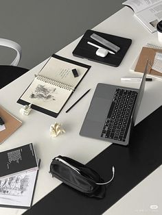 a laptop computer sitting on top of a white desk next to a black and white bag