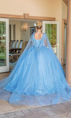 a woman in a blue wedding dress is looking at the back of her gown as she stands outside