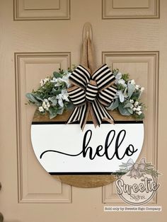 a door hanger that says hello with flowers and greenery on the front porch