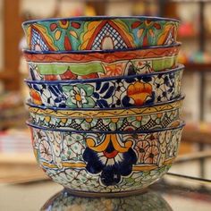 a stack of colorful bowls sitting on top of a glass table