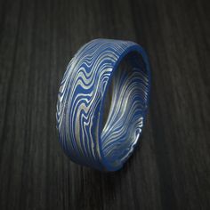 This Marble Damascus Steel ring features:- A Beveled Shape- A Polish Kuro Damascus Finish- 8mm Width- Cerakote Grooves Blue Round Etched Jewelry, Blue Etched Round Jewelry, Damascus Steel Ring, Black Diamond Ring, Ceramic Coating, Men's Ring, Damascus Steel, Steel Ring, Damascus