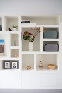 a white shelf with flowers and pictures on it