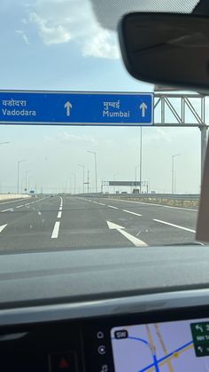 the view from inside a car looking at a highway sign and direction to mumbai, india