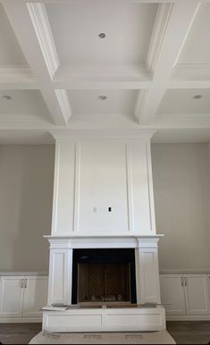 an empty living room with white painted walls and ceiling tiles on the fireplace mantel