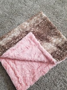 the blanket is laying on the floor with it's pink and brown color scheme