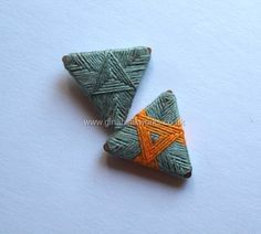 two small green and orange triangles on a white surface