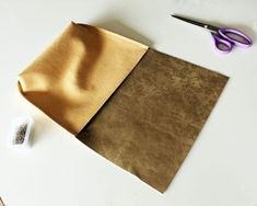 a piece of brown paper next to a pair of scissors on top of a table