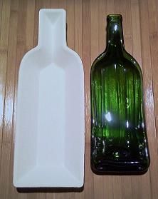 a green glass bottle sitting next to a white plastic container on a wooden table top