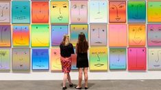 two women standing in front of a colorful wall