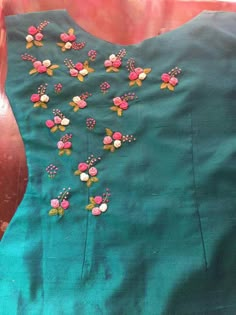 a green dress with pink and white flowers on the front, sitting on a table