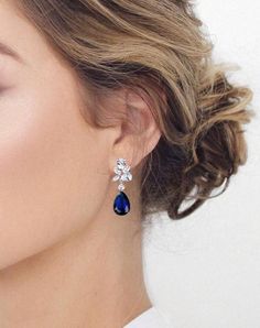 a close up of a woman's face wearing earrings with blue stones on them