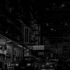 a black and white photo of cars parked on the side of a street at night