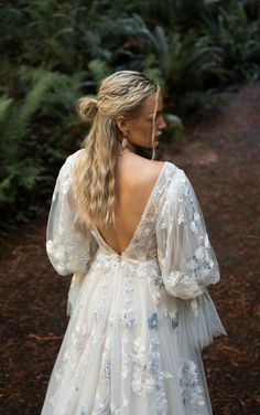 a woman wearing a white dress with flowers on it and long hair in the back