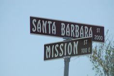 two street signs that are on top of a pole in front of a tree and blue sky