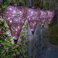 three purple lights hanging from the side of a fence