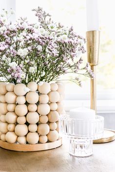 a wooden bead vase sitting on top of a table next to a glass cup filled with flowers