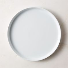 an empty white plate sitting on top of a table