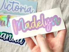 a person holding up a sticker with the word madelyn on it in different colors