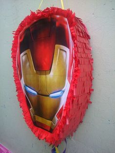 the iron man mask is hanging on the wall next to a balloon with streamers around it