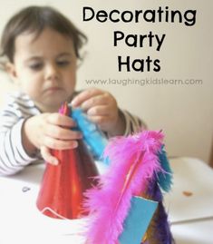 a young boy is decorating party hats with pink, blue and purple feathers on the table