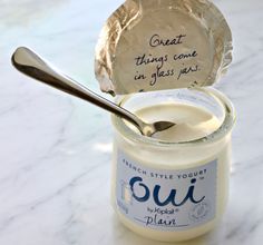 a jar of yogurt with a spoon in it sitting on a marble table