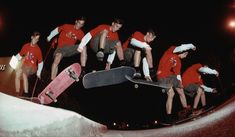 a group of young men riding skateboards on top of a snow covered slope at night